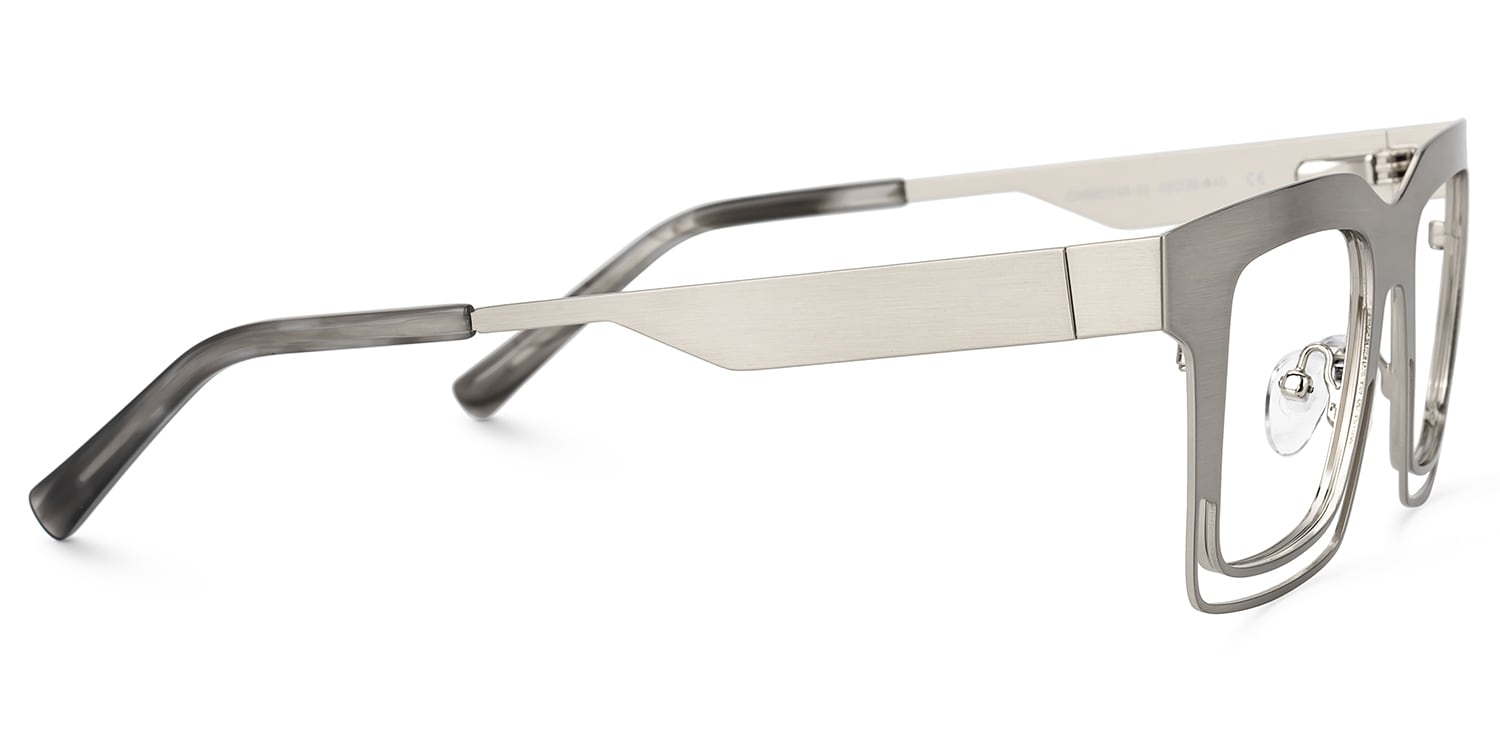 Lentes graduados cuadrados oversized en metal plata mate con diseño geométrico de líneas abiertas. Un armazón moderno, elegante y de inspiración vanguardista que combina ligereza visual y sofisticación.