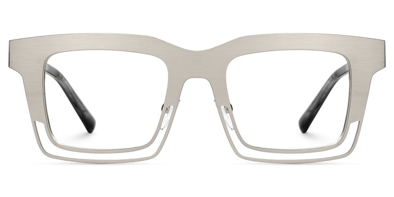 Lentes graduados cuadrados oversized en metal plata mate con diseño geométrico de líneas abiertas. Un armazón moderno, elegante y de inspiración vanguardista que combina ligereza visual y sofisticación.